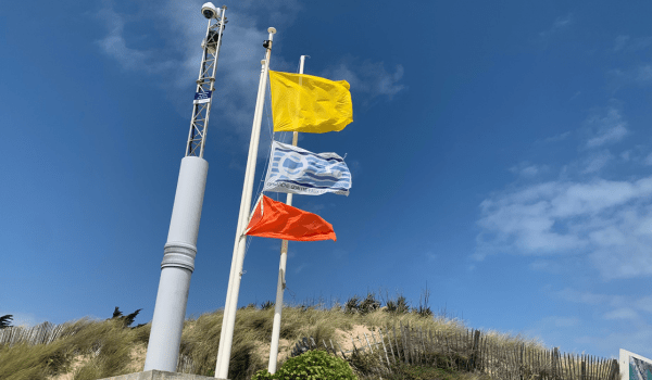 Drapeau jaune et orange flottant sur une plage de l'île de Ré en vue de vagues et vents importants, vent, vague, tempête